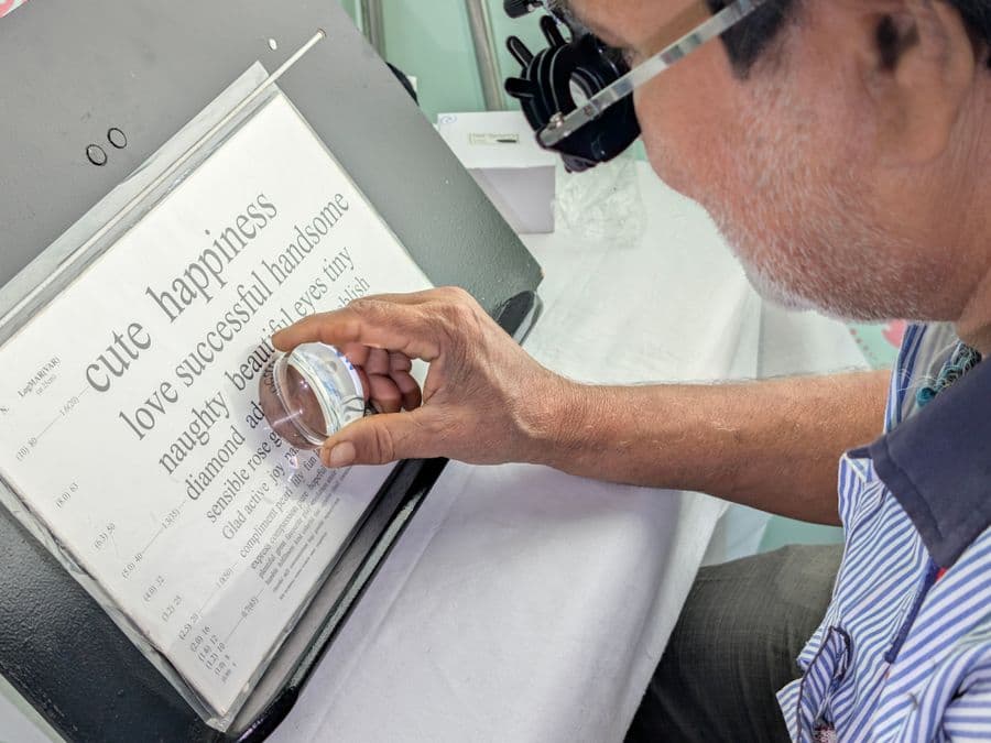 Patient reading an eye test chart with a magnifying glass